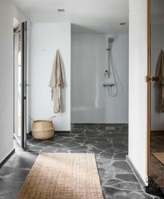 a bathroom with stone flooring and white walls, along with an area rug that has been placed on the floor