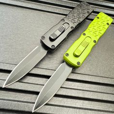 two knives sitting next to each other on top of a metal surface with green handles