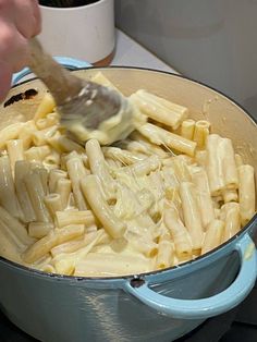 someone is stirring pasta into a pot on the stove