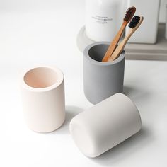 two toothbrushes are sitting in a cup next to an empty tube and container