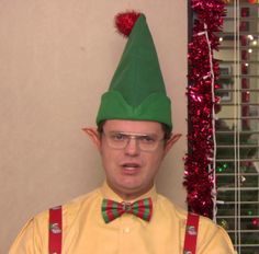 a man wearing a green elf hat and bow tie with suspenders on his head