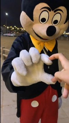 a person in mickey mouse costume holding out their hand