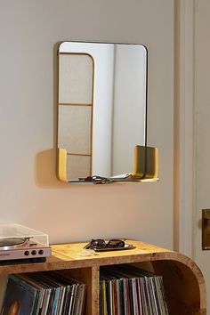 a record player sitting on top of a wooden table next to a wall mounted mirror