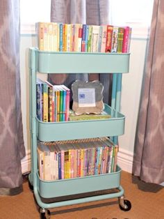 a blue cart with books on it in front of a window