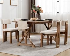 a wooden table with four chairs and a vase on top of it in front of a window