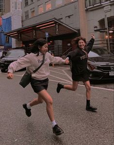 two girls are running down the street together