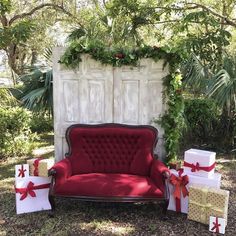 a red couch sitting in front of a white door with presents on the ground next to it