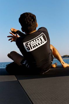 a man sitting on the edge of a boat looking at something in the air with his hands out