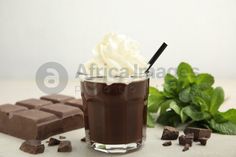 there is a chocolate drink with whipped cream in the cup and mint on the side