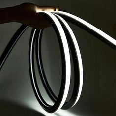 a hand holding a black and white cord with light coming from it's end