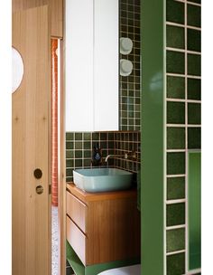 a bathroom sink sitting under a mirror next to a wooden door and cabinet with mirrors on it