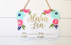 a sign that says alvia tea with flowers on it hanging from the side of a wall