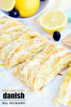 lemon cream cheese danish bread with blueberries and lemons in the background on a white surface