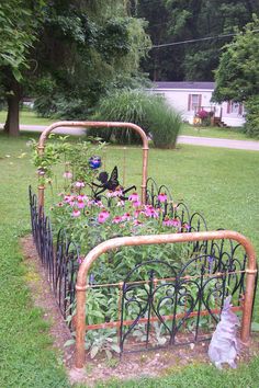 an iron garden bed with pink flowers growing in it