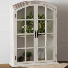 an old white china cabinet with glass doors and flowers in it's display case