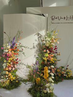 three tall vases filled with colorful flowers on top of a white cloth covered table