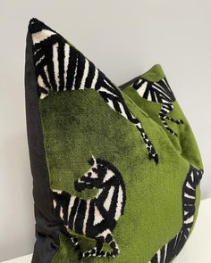 a green and black pillow with zebras on it