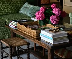 a living room filled with furniture and flowers on top of a wooden table next to a green couch