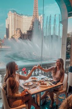 two women sitting at a table with food in front of the eiffel tower