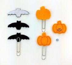 three paper clips with different types of halloween decorations on them, one has a bat and the other has a pumpkin