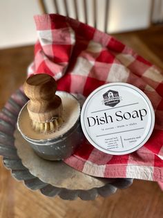 the dish soap is sitting on top of an old metal container with a wooden brush in it