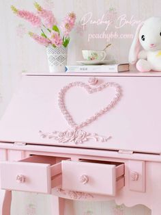 a pink desk with drawers and a stuffed animal on top