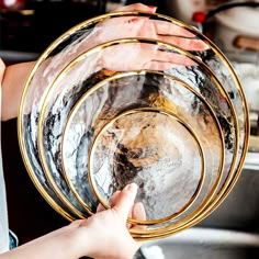 two people holding plates in their hands while they are washing dishes on the kitchen sink