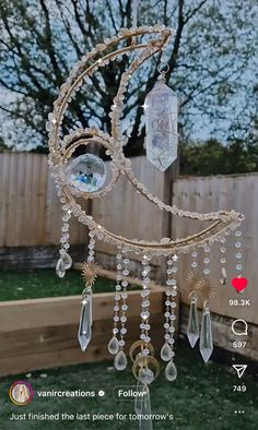 a wind chime hanging from the side of a fence in front of a tree