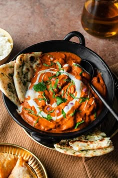 a pan filled with food on top of a table next to pita bread and dip