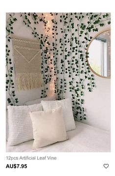 a white bed topped with pillows next to a window covered in green ivy leaves and a round mirror