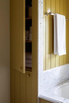 a bathroom with yellow walls and white marble counter tops, along with a bathtub