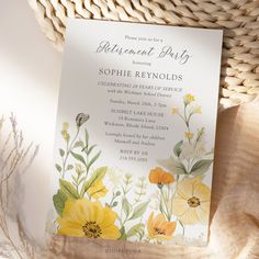 a white and yellow floral themed party card on a wicker basket filled with flowers