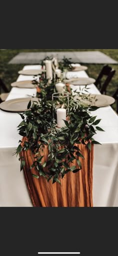 the table is set with white linens and greenery for an outdoor wedding reception