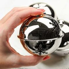 a person holding a glass ball in front of two black and white balls on a table