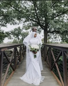 a bride standing on a bridge with her bouquet in hand and looking at the camera