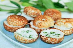 small pastries with cream cheese and herbs on a blue plate next to some flowers