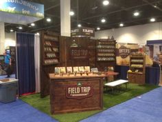 a booth at a trade show with signs on the wall and green carpeted floor