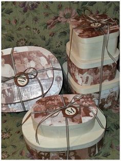 three cakes wrapped in brown and white paper with bows on them sitting on a table