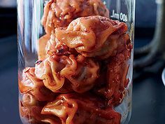 a jar filled with lots of food sitting on top of a black table next to a knife