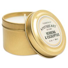 a candle in a gold tin with the lid open to show it's label