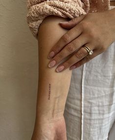 a woman's arm with a small tattoo on the left side of her wrist