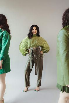 a woman standing in front of three mannequins wearing green clothing and heels