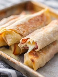 two burritos sitting on top of a pan with cheese and meat in them