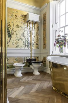 an ornate bathroom with gold fixtures and wallpaper, along with a claw foot tub