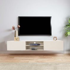 a flat screen tv sitting on top of a white entertainment center next to a potted plant