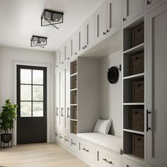 an empty room with white cabinets and black doors, along with bookshelves that have baskets on them