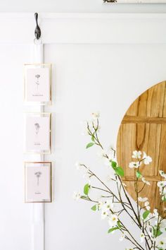 a vase filled with white flowers sitting next to a wooden plaque on the wall above it