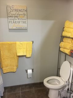 a white toilet sitting next to a yellow towel on top of a rack in a bathroom