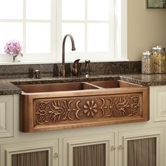 a kitchen sink with an intricate design on the front and side panel, in copper