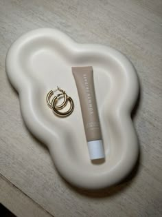 a tube of cream sitting on top of a white plate next to a gold ring